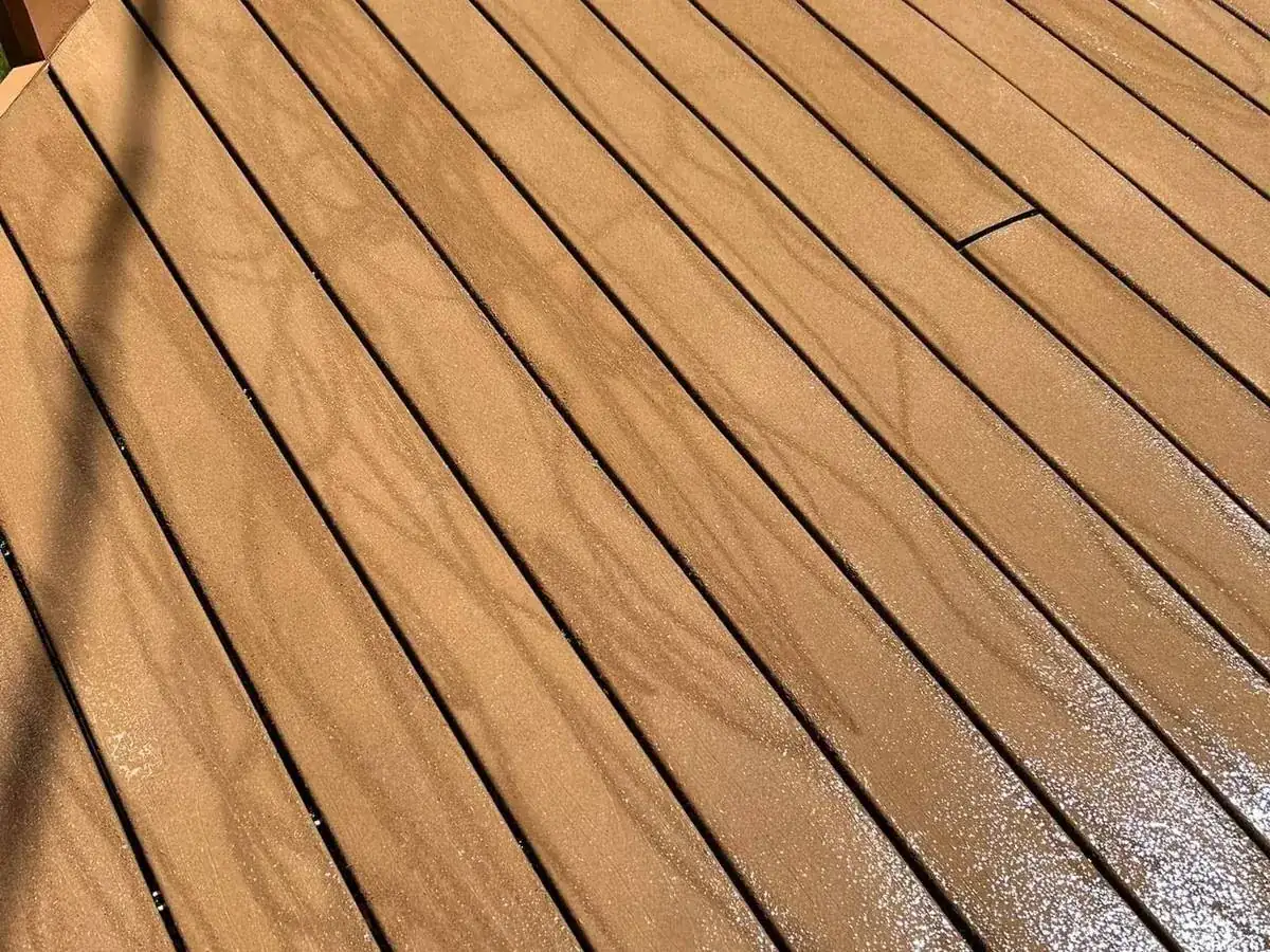 Composite deck boards with the embossed surface cut away in sweeping arcs
