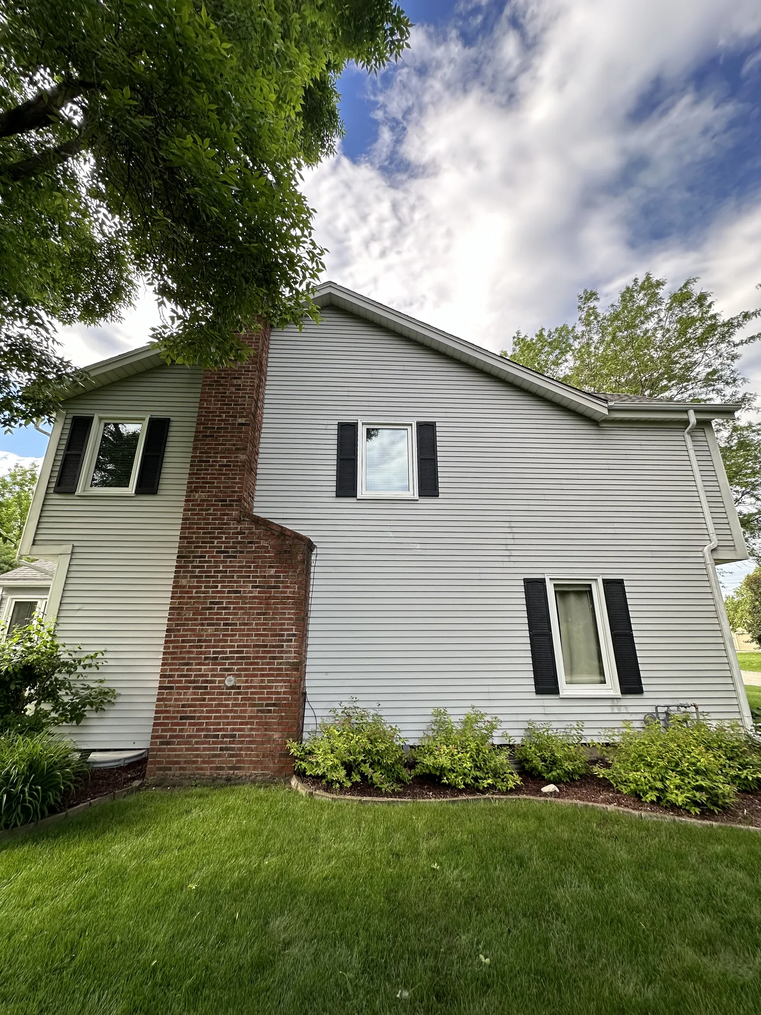 Gable end and brick chimney of the Brookfield home after soft washing, siding back to an even color