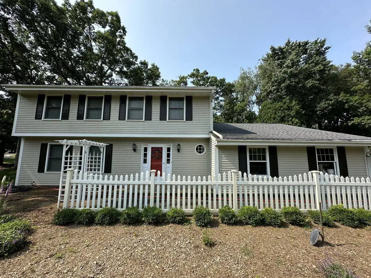 Front elevation of a Delafield home before soft washing, siding dulled under heavy oak cover